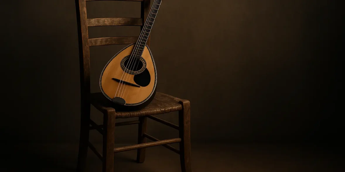 Μπουζούκι τοποθετημένο πάνω σε μια παλιά ξύλινη καρέκλα, με ζεστό φωτισμό και σκούρο φόντο.