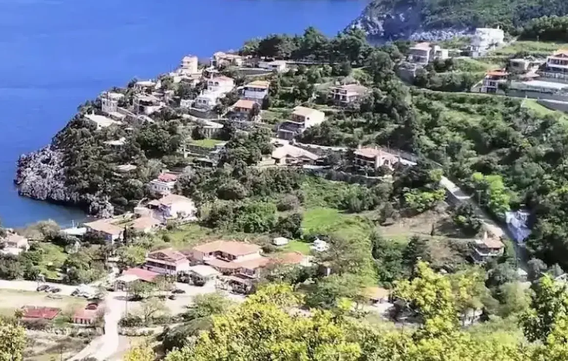 Πανοραμική θέα της Αγίας Σοφίας στην Εύβοια, με καταπράσινες πλαγιές, σπίτια με κεραμοσκεπές και στο βάθος το ρέμα που κατηφορίζει προς τον Λιμνιώνα. Ήπιο απογευματινό φως και καθαρός ουρανός.