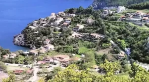 Πανοραμική θέα της Αγίας Σοφίας στην Εύβοια, με καταπράσινες πλαγιές, σπίτια με κεραμοσκεπές και στο βάθος το ρέμα που κατηφορίζει προς τον Λιμνιώνα. Ήπιο απογευματινό φως και καθαρός ουρανός.