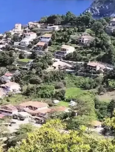 Πανοραμική θέα της Αγίας Σοφίας στην Εύβοια, με καταπράσινες πλαγιές, σπίτια με κεραμοσκεπές και στο βάθος το ρέμα που κατηφορίζει προς τον Λιμνιώνα. Ήπιο απογευματινό φως και καθαρός ουρανός.