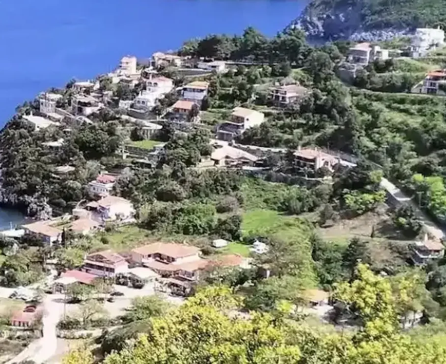 Πανοραμική θέα της Αγίας Σοφίας στην Εύβοια, με καταπράσινες πλαγιές, σπίτια με κεραμοσκεπές και στο βάθος το ρέμα που κατηφορίζει προς τον Λιμνιώνα. Ήπιο απογευματινό φως και καθαρός ουρανός.