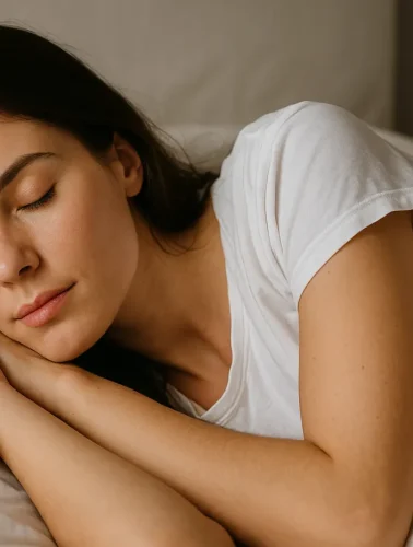 Γυναίκα κοιμάται ήρεμα σε λευκό κρεβάτι, συμβολίζοντας τα όνειρα και την ψυχική ηρεμία.